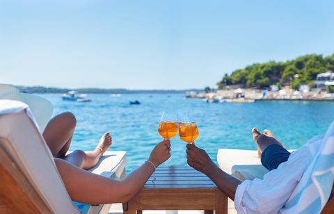 couple relaxing and toasting with a spritz cocktail on a beach deck over the ocean