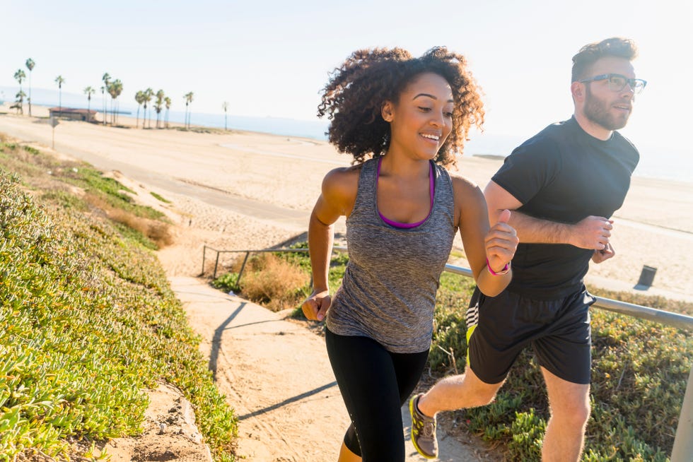 Couple running along pathway by beach