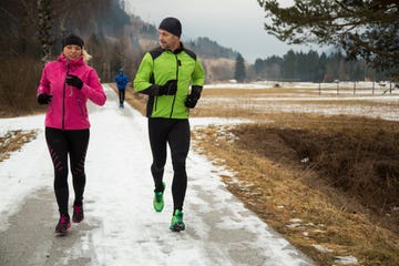 una pareja corre en el frío gélido abrigada con gorro, guantes, mallas largas y cortavientos