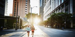couple waterproof running together on empty city street during workout at sunrise