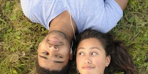 couple sharing headphones in grass