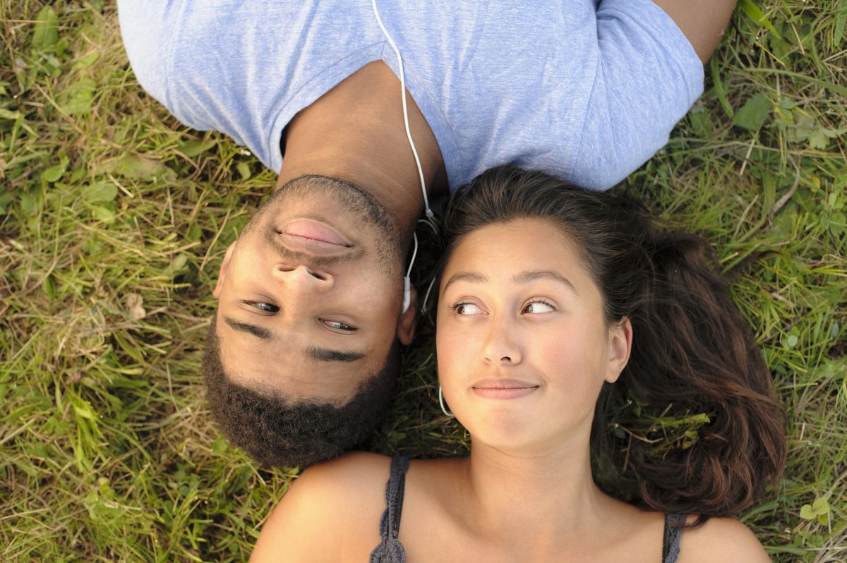 couple sharing headphones in grass