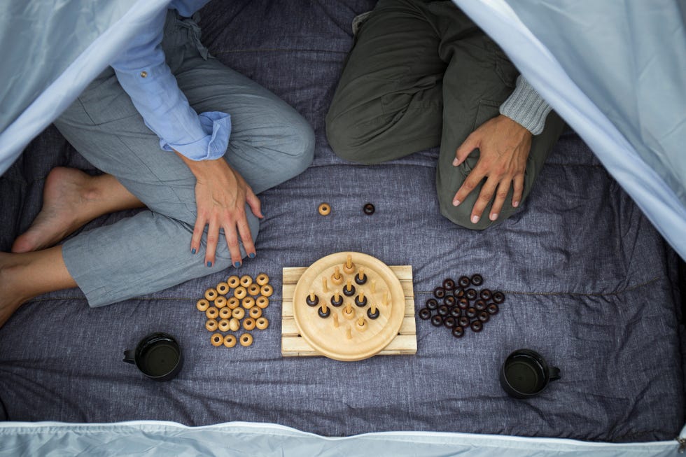 couple sitting in tent playing board game, partial view