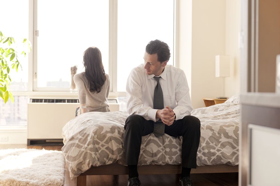 couple sitting on bed after argument at home
