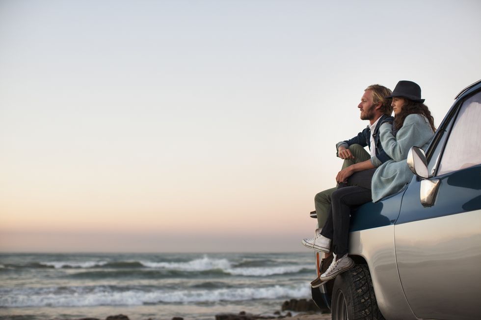 couple sitting on truck looking at ocean view
