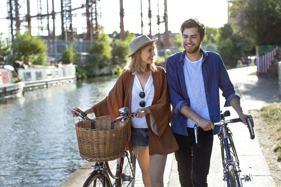couple smiling and walking along canal with bikes