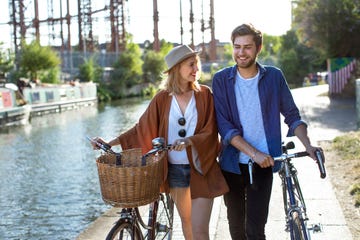 couple smiling and walking along canal with bikes