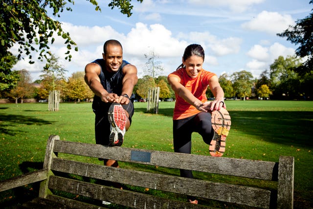 couple stretching legs on park bench