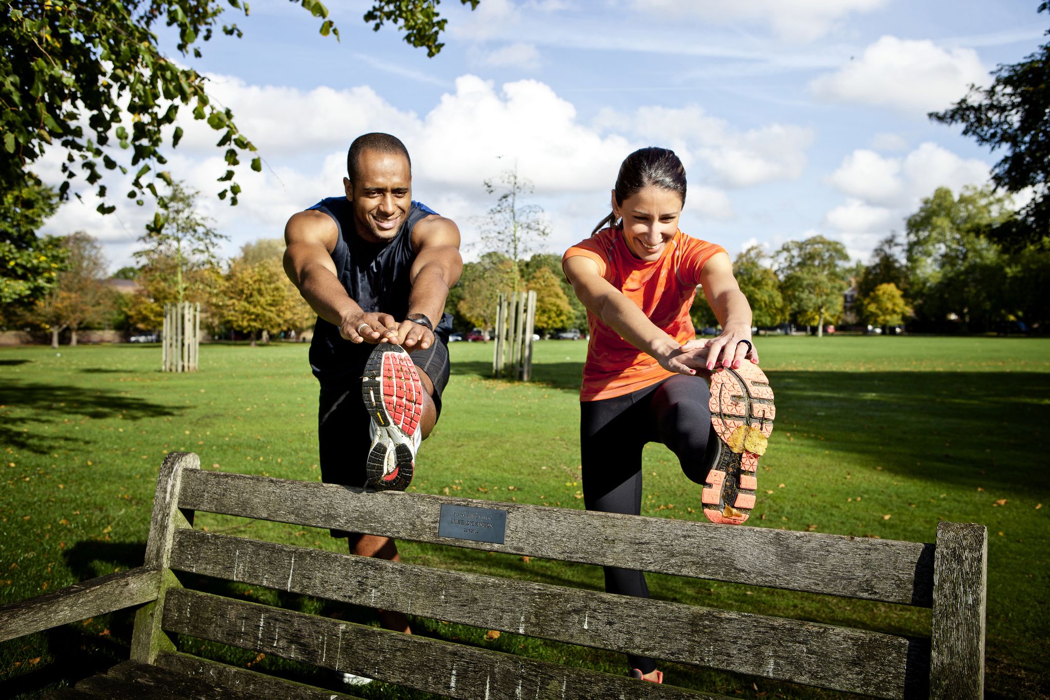 couple stretching legs on park bench