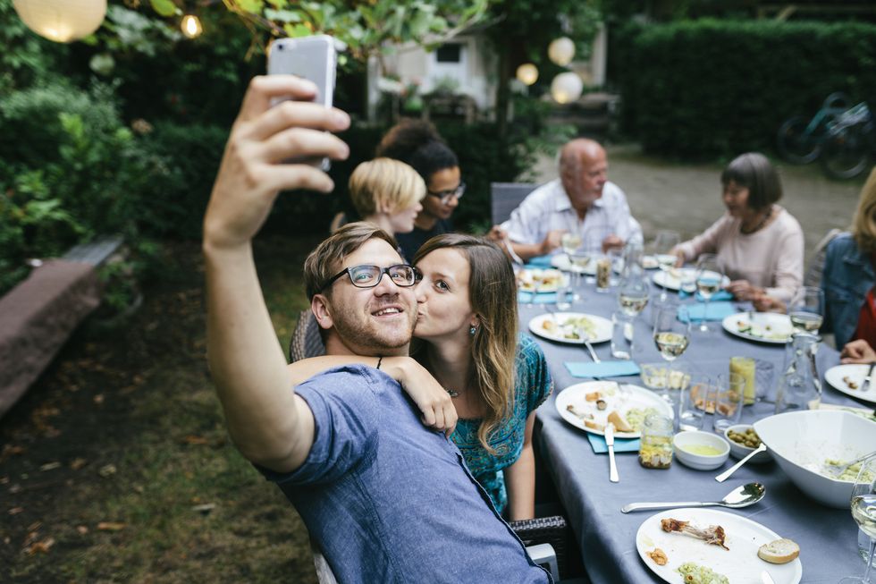 couple taking selfie during bbq with family