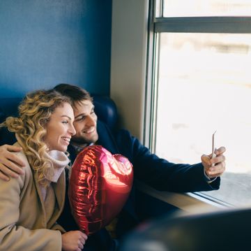 Couple taking selfie with heart shaped balloon inside train