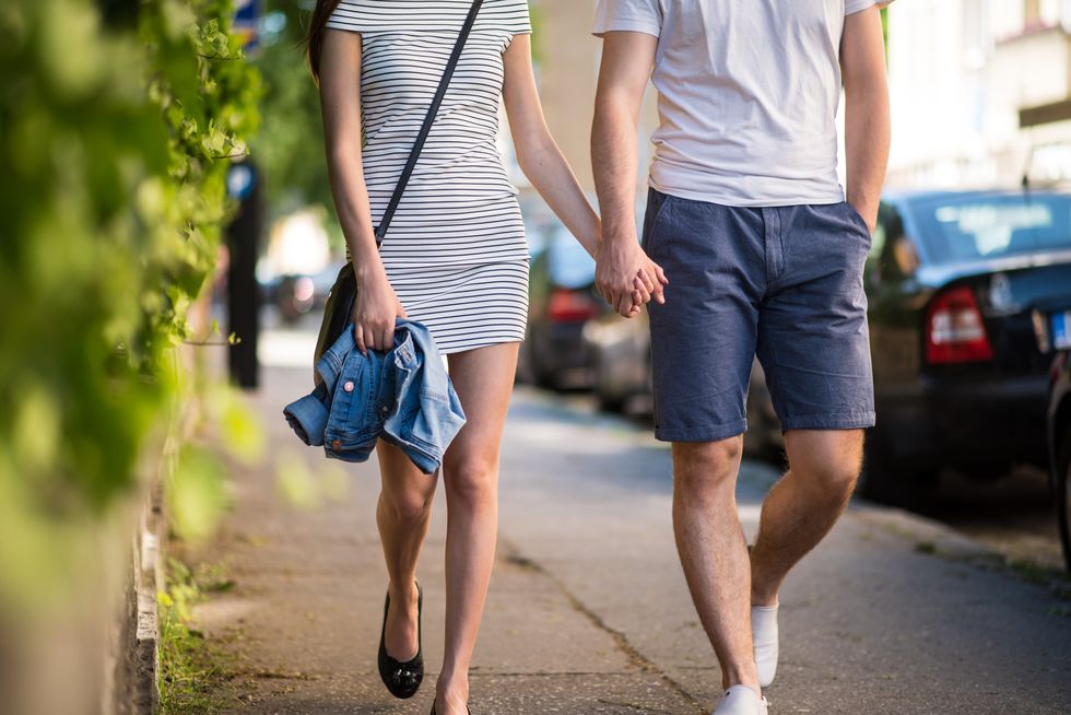 Couple walking on sidewalk with hand in hand