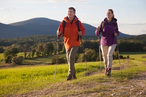 couple walking with poles in meadow