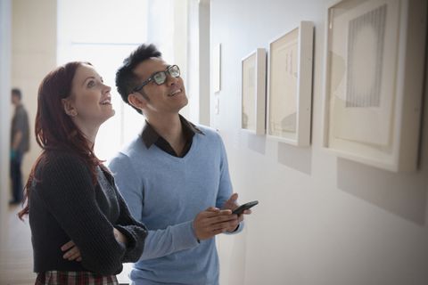 Couple with cell phone admiring artwork in gallery