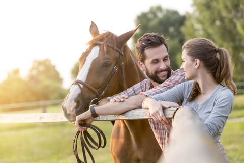 Couple with horse talking at rural pasture fence