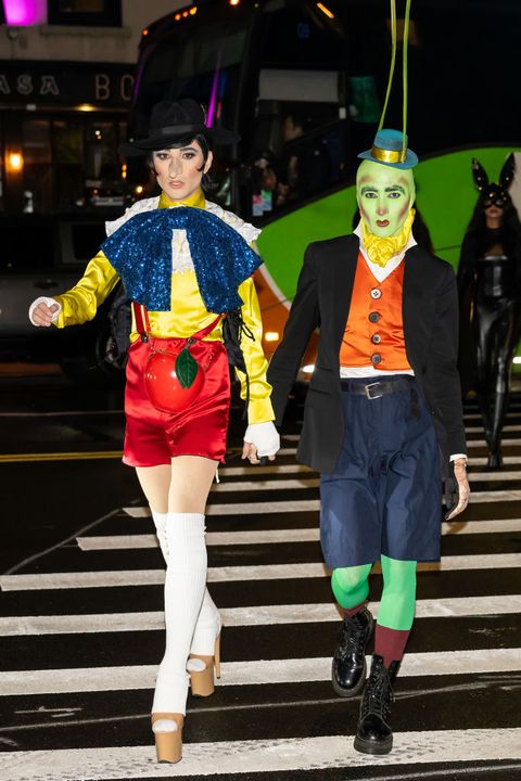 couples costumes, man and woman dressed as pinocchio and cricket walking across the street