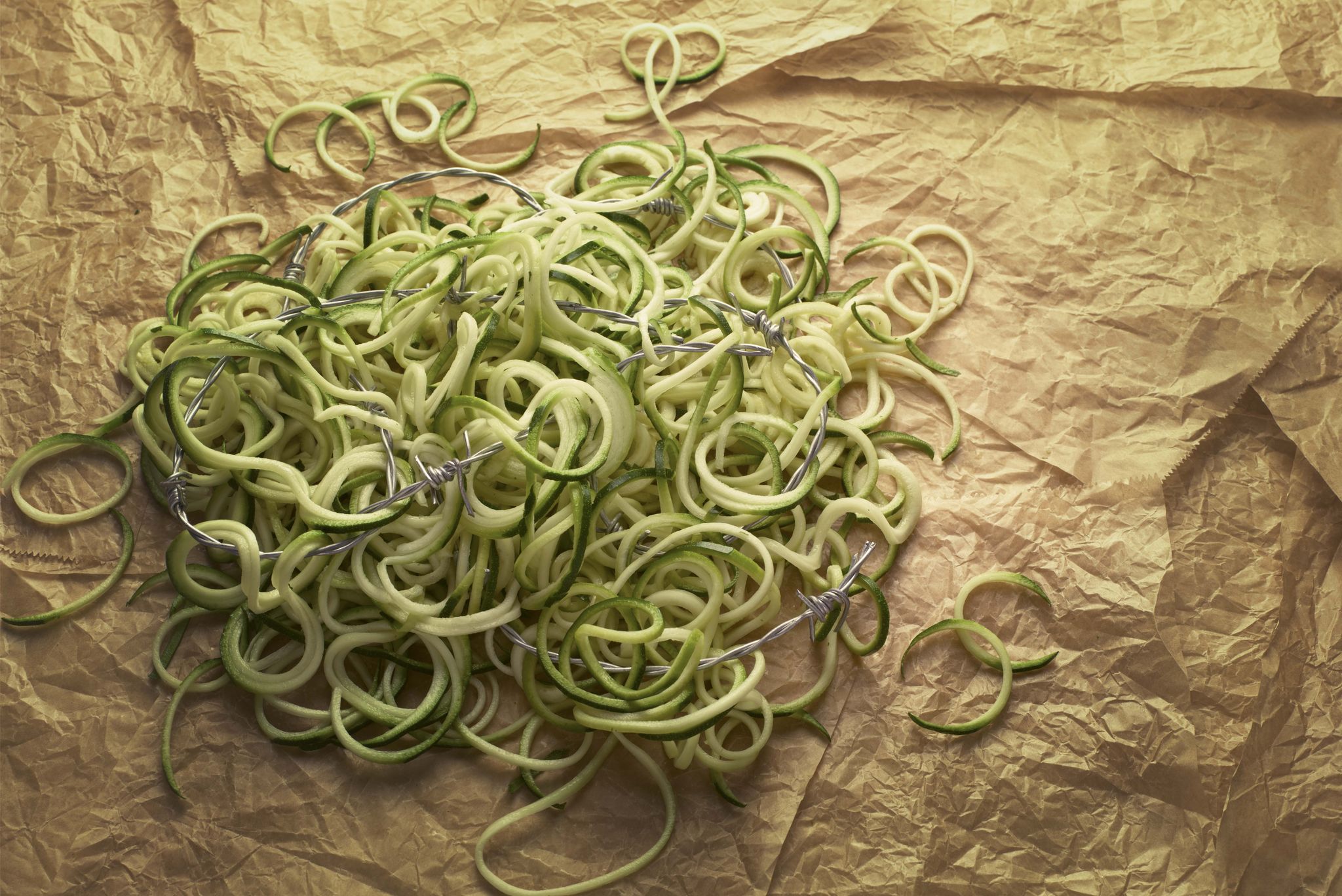 a pile of courgette spagettii courgetti on a brown paper bag with barbed wire running through it