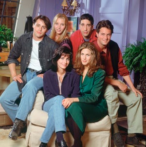 friends cast photo from season 1, including matt leblanc, lisa kudrow, david schwimmer, matthew perry, jennifer aniston, and courteney cox sitting on an armchair