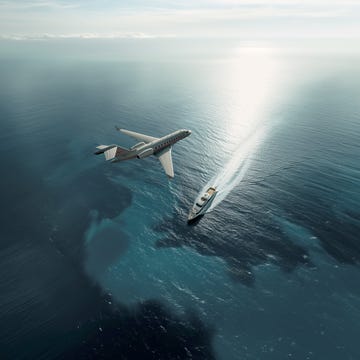 a jet flying above a yacht on the ocean