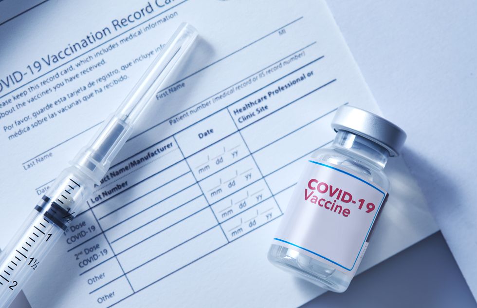 covid 19 vaccination record card with a vial of a covid 19 booster dose