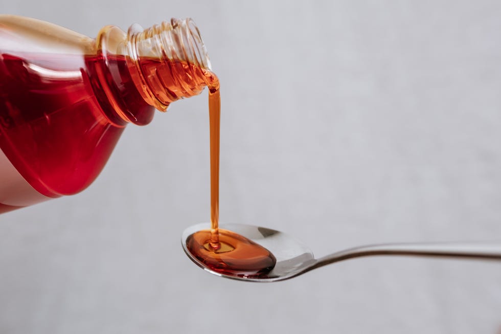 covid liquid medicine bottle being poured out onto a metal spoon