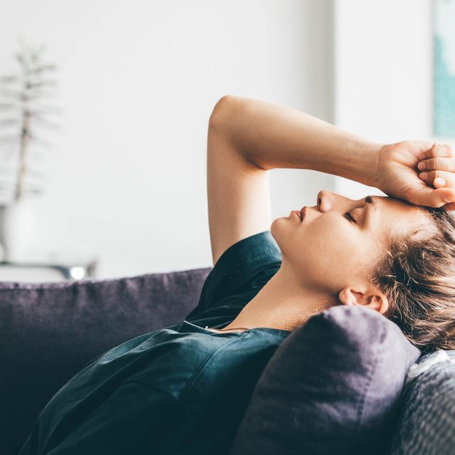 sad woman leans head on sofa as she closes her eyes