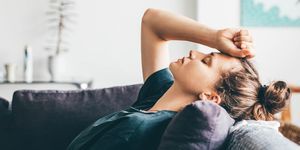 sad woman leans head on sofa as she closes her eyes