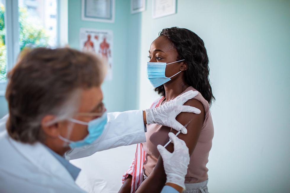 black woman wearing a face mask receiving an injection