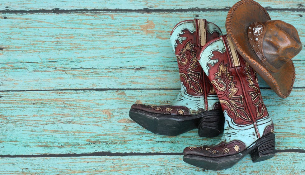 cowboy boots and hat laying on a teal painted wood background