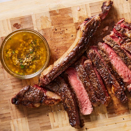 herb butter in a bowl with sliced grilled steak