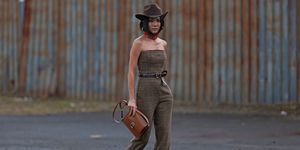 a person in a jumpsuit and cowboy hat holding a purse