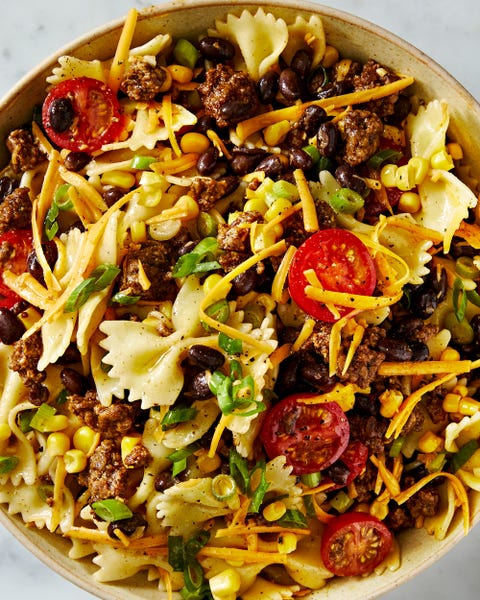 cowboy pasta salad with halved cherry tomatoes, ground beef, black beans, sliced scallions, and shredded cheddar