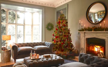 living room with christmas tree with red decorations and a marble fireplace