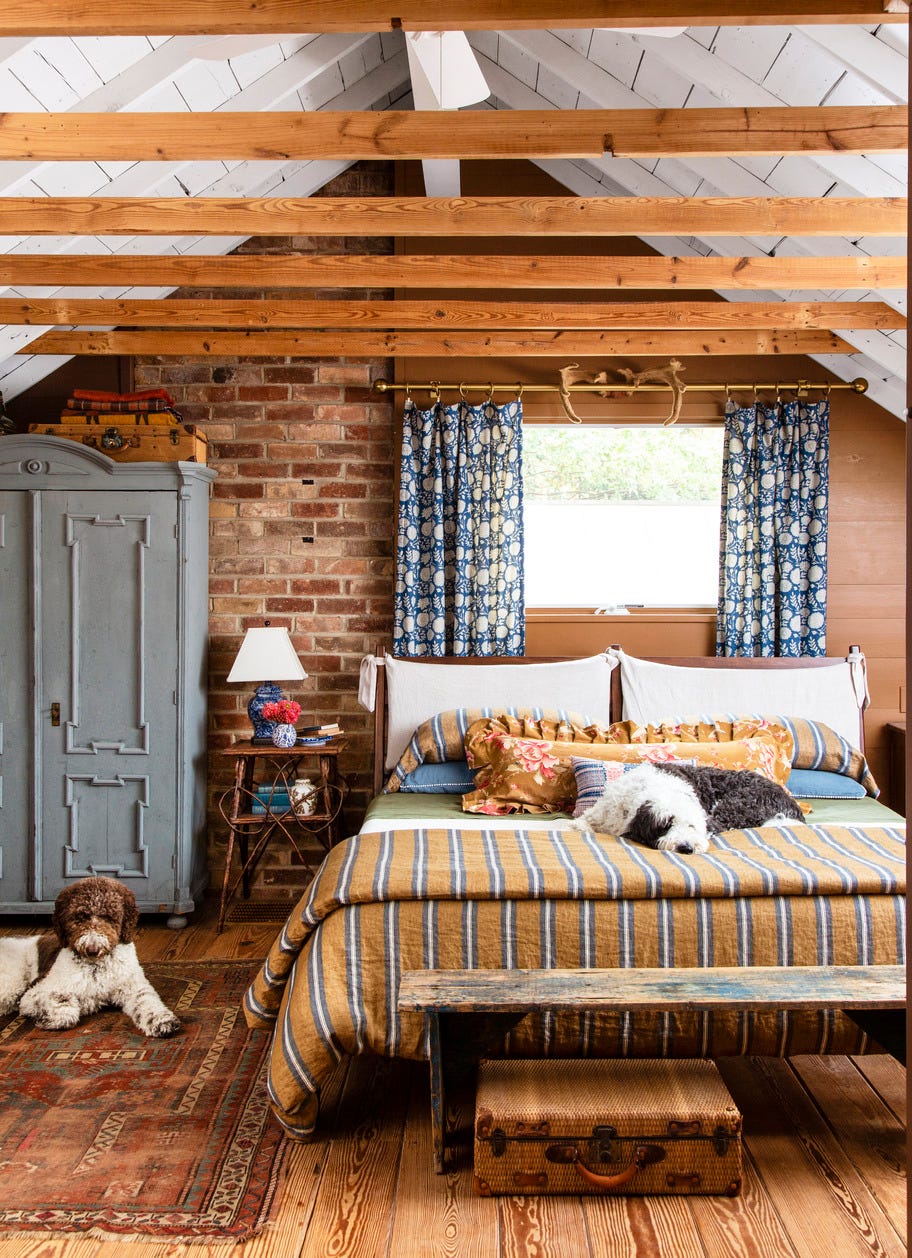 cozy bedroom with brick wall and wood rafters with dog on bed