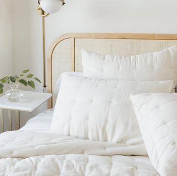 a bed with white sheets and an off white quilt