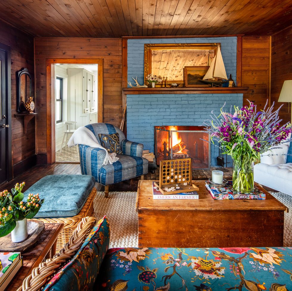 1910 bungalow overlooking valentine lake in michigan designed by erica harrison that has a blue fireplace and blue and wood furniture