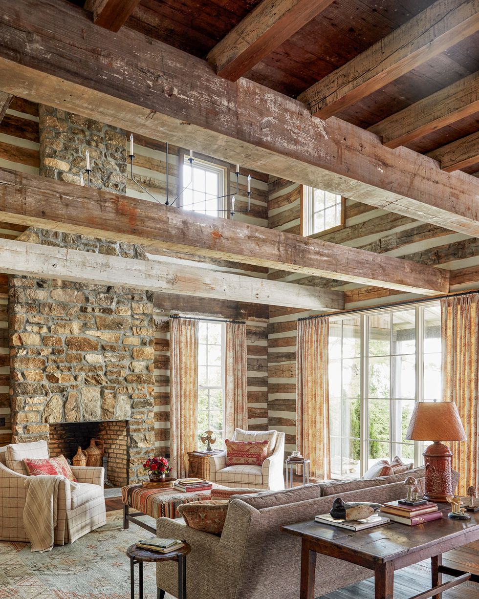 a mountain house with a stone fireplace and beams across the living room