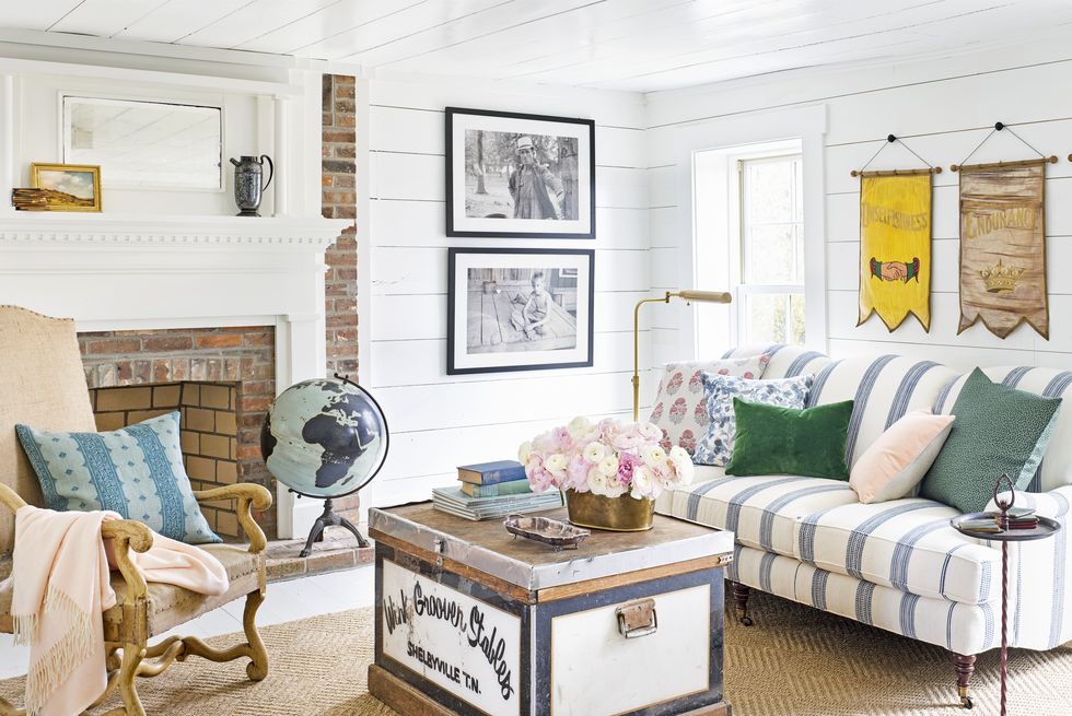 a living room with a striped couch and white shiplap walls
