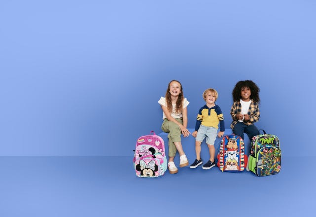 children sitting with colorful backpacks against a blue backdrop