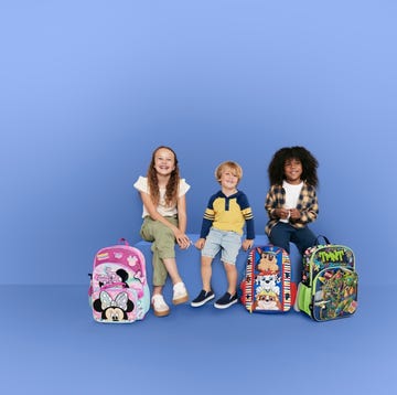 children sitting with colorful backpacks against a blue backdrop children sitting with colorful backpacks against a blue backdrop