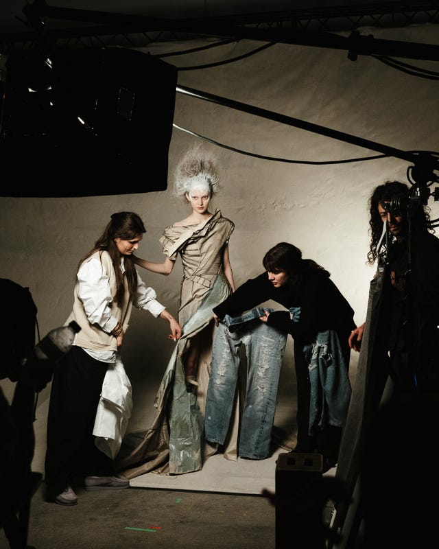 ensaio fotográfico de moda com modelos e estilistas ajustando trajes
