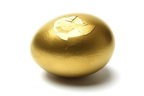 cracked golden egg on white background