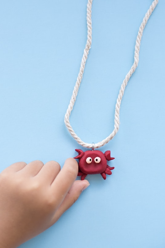 crafts for kids, hand holding a red crab necklace made of clay
