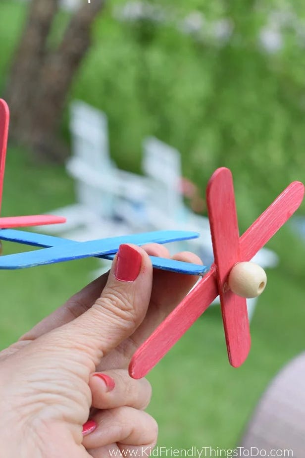crafts for kids, craft stick airplane crafts for kids, hand holding a craft stick airplane outdoors