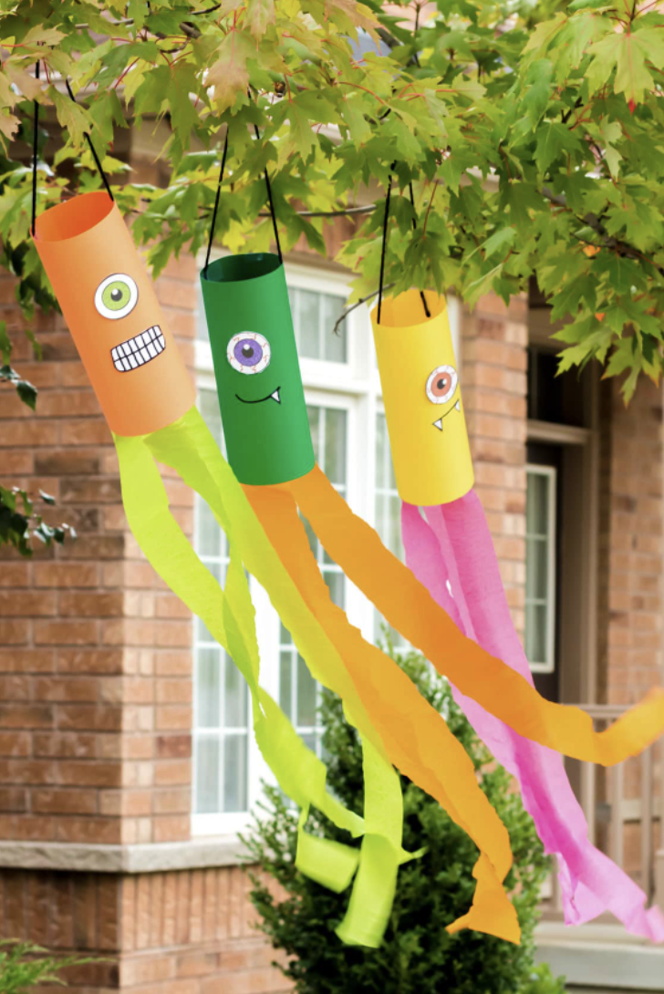 crafts for kids, diy monster windsocks hanging from a tree outdoors