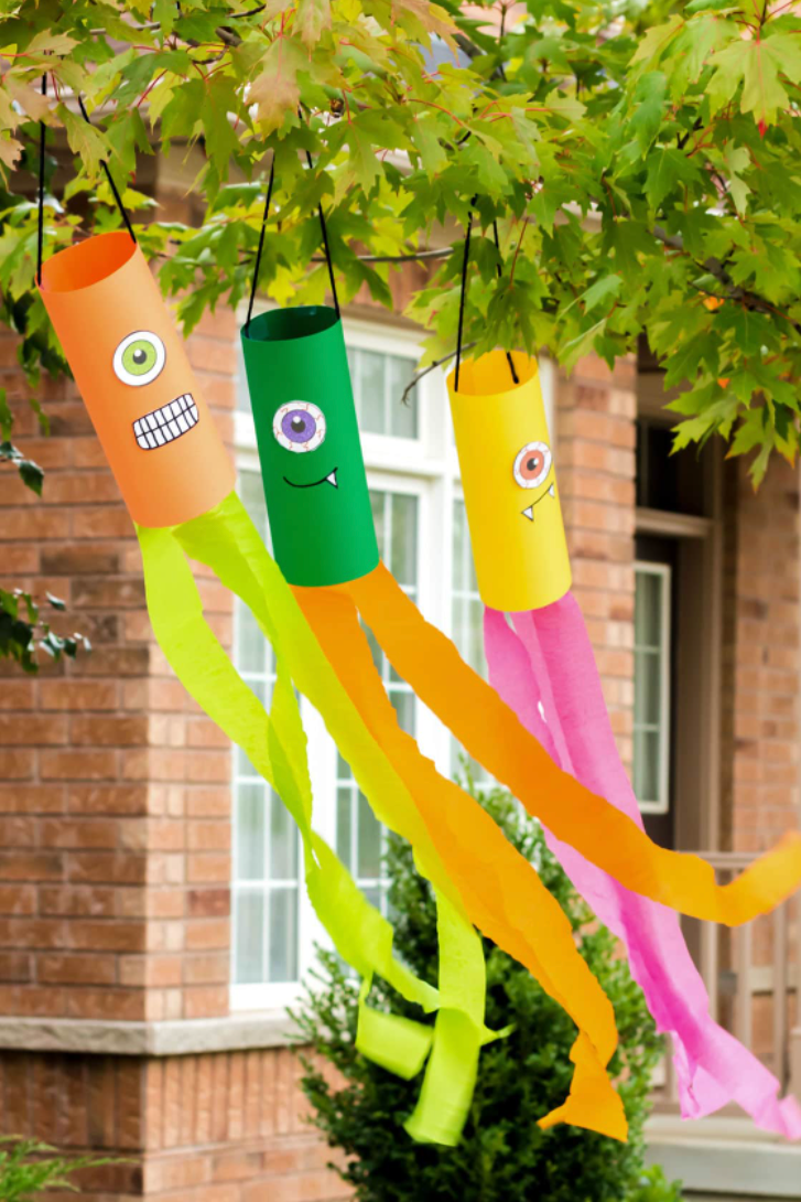 crafts for kids, diy monster windsocks hanging from a tree outdoors