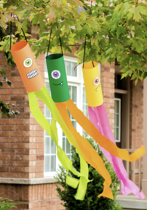 crafts for kids, diy monster windsocks hanging from a tree outdoors