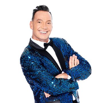 craig revel horwood smiling with his arms folded