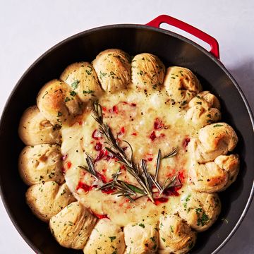 brie dip in a cast iron skillet swirled with cranberry sauce and surrounded by herby biscuits