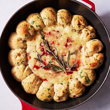 brie dip in a cast iron skillet swirled with cranberry sauce and surrounded by herby biscuits